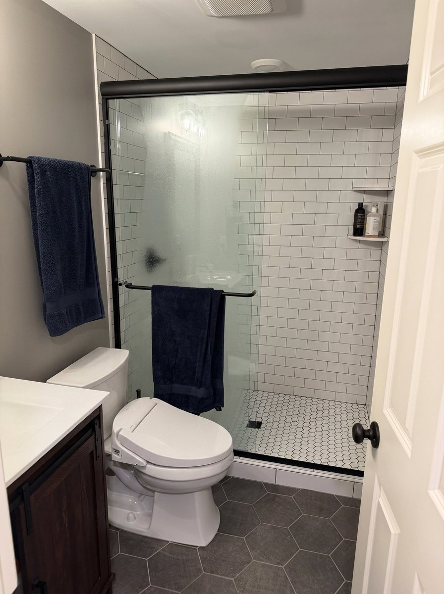 Bathroom before: builder-grade subway tile shower and dark hex floor